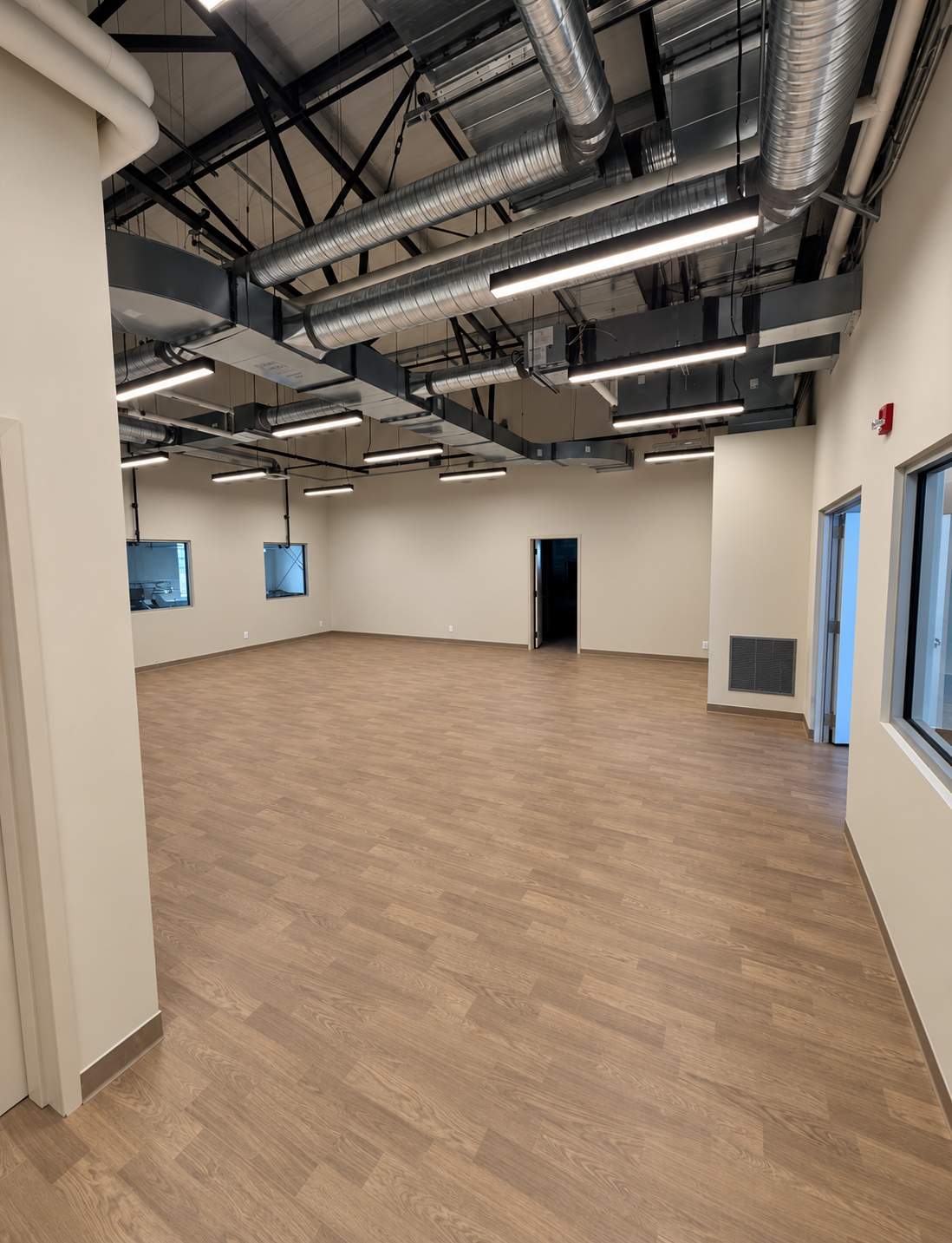Completed open-ceiling commercial room with linear lighting and exposed services